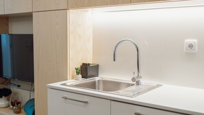 Una cocina moderna con un lavamanos de acero inoxidable, armarios de madera y un televisor integrado.