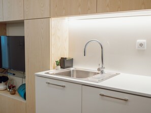 Eine moderne Küche mit Spüle aus Edelstahl, Holzschränken und einem integrierten Fernseher.