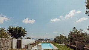 Una piscina con sillas de descanso y un muro de piedra.