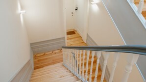 Una escalera de madera con balaustres blancos que lleva a una puerta.