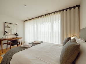 A hotel room with a bed, a desk, a chair, a map on the wall, and a window with curtains. - DOWNTOWN PENTHOUSE with RIVER VIEW by VACATIONY by Interhome (Porto)