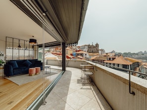 A modern balcony with a sofa and ottomans, overlooking a cityscape with historic buildings. - DOWNTOWN PENTHOUSE with RIVER VIEW by VACATIONY by Interhome (Porto)