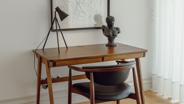 Een houten bureau met een lamp en een buste.