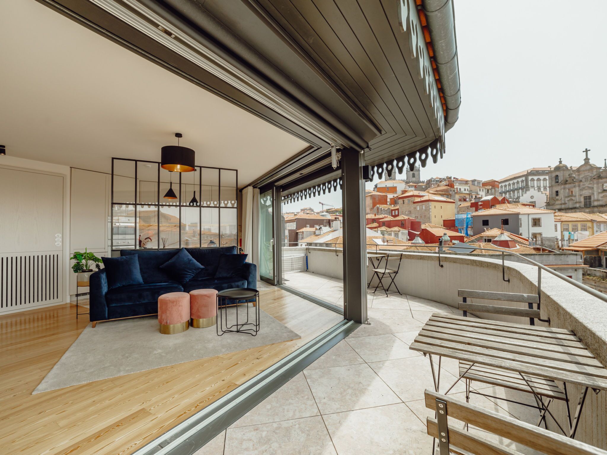 A modern living room with a dark blue sofa, a wooden coffee table, and a view of the cityscape through large windows.