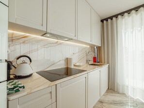 A modern kitchen with white cabinetry, a marble backsplash, a built-in oven, and a stainless steel sink. - DOWNTOWN PENTHOUSE with RIVER VIEW by VACATIONY by Interhome (Porto)