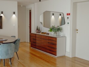 A modern interior with a dining area, a wooden cabinet with a mirror, and a red emergency exit sign. - DOWNTOWN PENTHOUSE with RIVER VIEW by VACATIONY by Interhome (Porto)