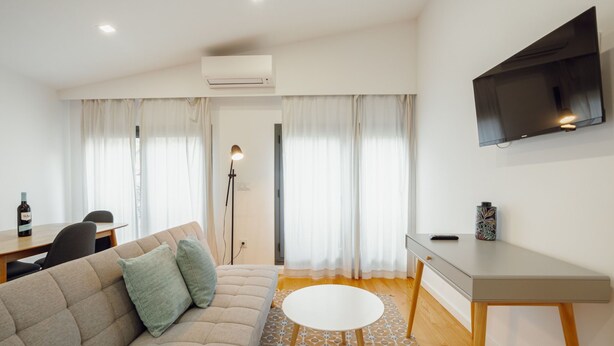 Uma sala de estar moderna com um sofá, uma escrivaninha, uma televisão e um tapete estampado.