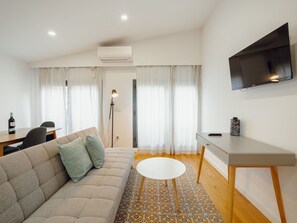 A modern living room with a sofa, a desk, a television, and a patterned rug. - Apartment  by Interhome (Porto)