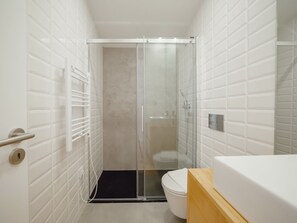 A modern bathroom with a glass-enclosed shower, a white toilet, and a wooden vanity. - Apartment  by Interhome (Porto)
