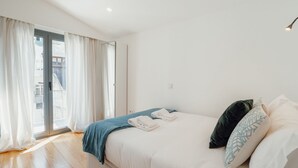 Um quarto com cama, janela com cortinas e vista para o exterior.