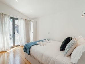 A bedroom with a bed, a window with curtains, and a view of the outside. - Apartment  by Interhome (Porto)