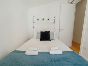 Ein Schlafzimmer mit Bett, Kissen, Nachttisch und einer Tür.