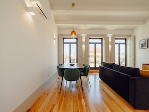 A modern living space with a dining area, a sofa, and large windows. - Apartment  by Interhome (Porto)