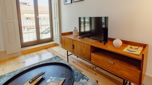 A modern living room with a flat-screen TV, wooden furniture, a remote control, and a magazine on a coffee table. - Apartment  by Interhome (Porto)