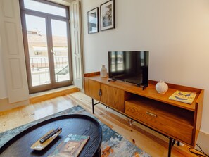 A modern living room with a flat-screen TV, wooden furniture, a remote control, and a magazine on a coffee table. - Apartment  by Interhome (Porto)