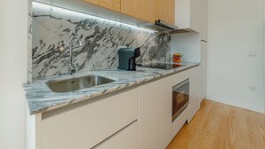 Een moderne keuken met een marmeren aanrecht, een roestvrijstalen spoelbak en houten kastjes.