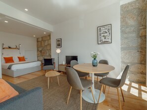 Ein modernes Wohnzimmer mit einer Couch, einem Esstisch mit Stühlen, einer Steinwand und einem gerahmten Bild.