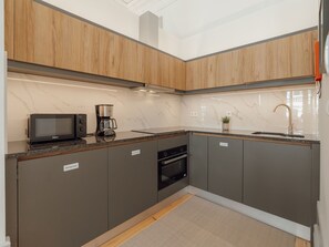 Eine moderne Küche mit Mikrowelle, Kaffeemaschine und Backofen.