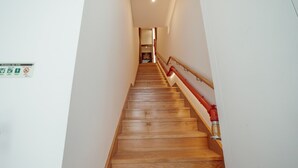 Una escalera de madera con barandilla roja que lleva a una habitación.