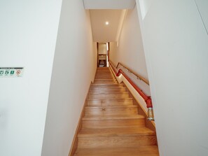 Eine Holztreppe mit roter Handlauf, die zu einem Raum führt.