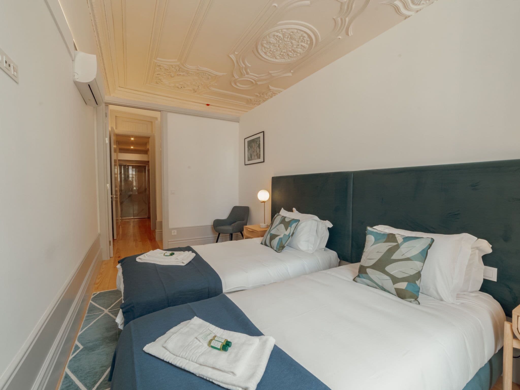 Une chambre d’hôtel avec deux lits, une chaise, un bureau et un tableau au mur.