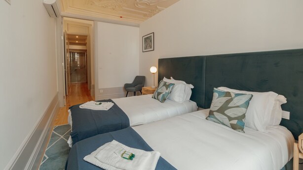 Una habitación de hotel con dos camas, una silla, un escritorio y un cuadro en la pared.