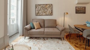 Una sala de estar moderna con un sofá color beige, una mesa de centro y un comedor con sillas.