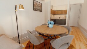 Comedor con una mesa redonda, cuatro sillas, un jarrón de flores y una lámpara de pie.
