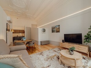 A modern living room with a sofa, a coffee table, a TV, and a dining area with chairs and a table. - Apartment  by Interhome (Porto)