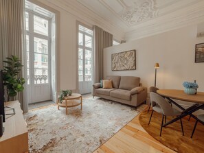 A modern living room with a sofa, a coffee table, and a dining area with chairs. - Apartment  by Interhome (Porto)