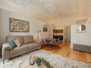 Uma sala de estar com um sofá, uma mesa de centro e um espaço de refeições com cadeiras.