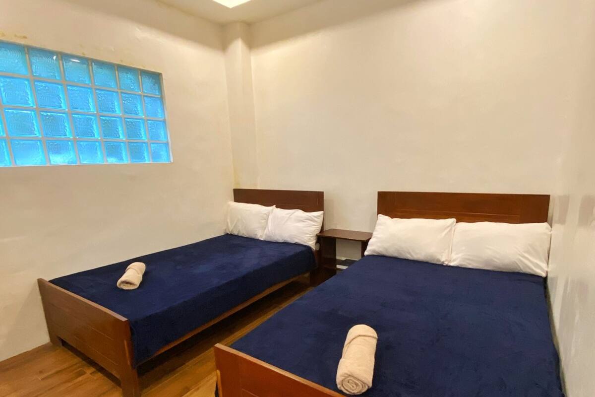 A room with two wooden beds, a wooden ceiling, and a window with frosted glass.