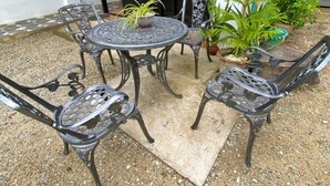 A patio with a round table and four chairs, surrounded by potted plants. - Sipalay Cozy Garden Stay (Sipalay)