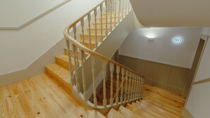 Eine Holztreppe mit weißen Geländern, die zu einer Zwischenebene führt.