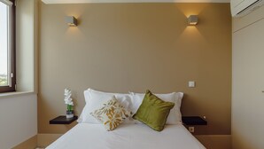 Ein Schlafzimmer mit einem großen Bett, zwei Nachttischen, einem Fenster und Wandleuchten.