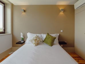Ein Schlafzimmer mit einem großen Bett, zwei Nachttischen, einem Fenster und Wandleuchten.