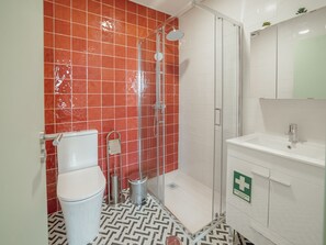 Et badeværelse med bruser, toilet og håndvask.
