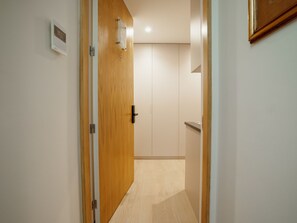 A hallway with a wooden door, a light switch, and a wall-mounted thermostat. - Apartment  by Interhome (Porto)