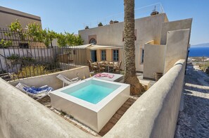 Un área de piscina moderna con sillones de descanso, una piscina pequeña y vistas al mar.