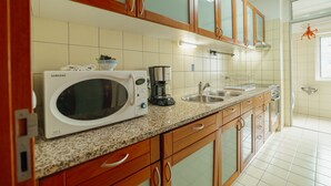 Uma cozinha com armários de madeira, micro-ondas, cafeteira e pia.