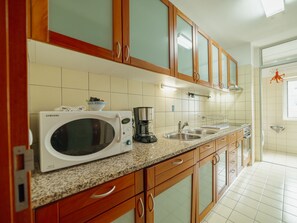 A kitchen with wooden cabinets, a microwave, a coffee maker, and a sink. - DOWNTOWN DELUXE 6 by VACATIONY by Interhome (Porto)