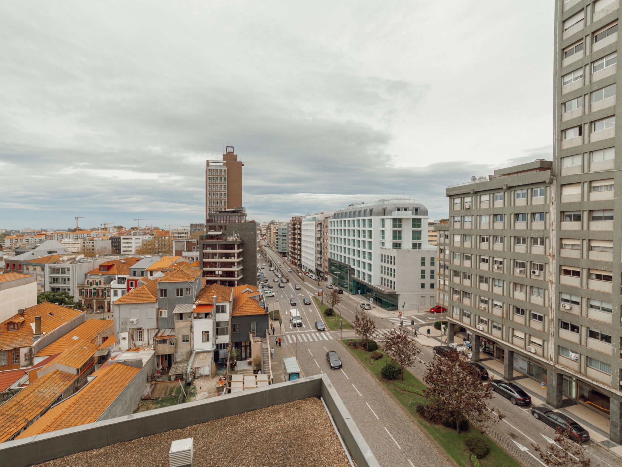 Un paisaje urbano con diversos edificios, incluyendo residenciales y comerciales, y una calle concurrida llena de automóviles.