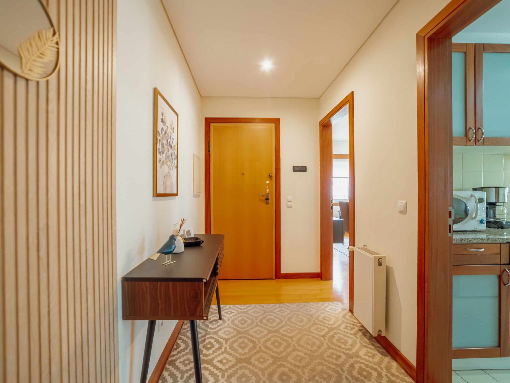 A hallway with a wooden door, a desk with a lamp, and a radiator.