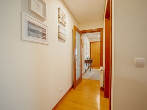 A hallway with framed pictures on the wall, a wooden floor, and a door leading to another room. - DOWNTOWN DELUXE 6 by VACATIONY by Interhome (Porto)