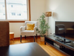 A modern living room with a sofa, armchair, and a television on a stand. - DOWNTOWN DELUXE 6 by VACATIONY by Interhome (Porto)