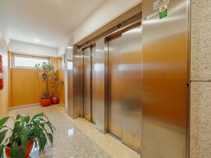 An elevator with a digital display, a wooden wall, and potted plants. - DOWNTOWN DELUXE 6 by VACATIONY by Interhome (Porto)