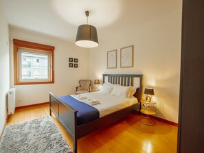 A bedroom with a bed, bedside lamps, a radiator, a window, and artwork on the wall. - DOWNTOWN DELUXE 6 by VACATIONY by Interhome (Porto)