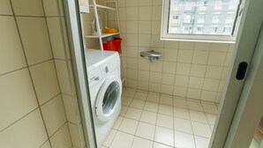 Uma lavanderia compacta com uma máquina de lavar Siemens, um varal e uma pequena janela.