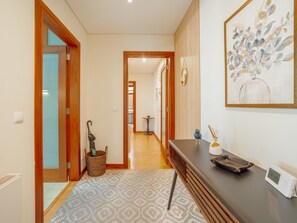 A hallway with wooden doors, a patterned rug, a small table with a bird figurine, and a wall-mounted artwork. - DOWNTOWN DELUXE 6 by VACATIONY by Interhome (Porto)