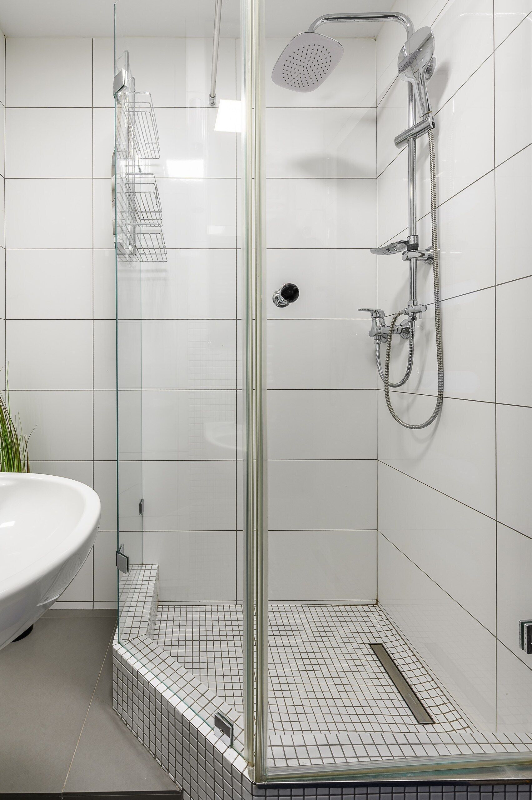 A modern bathroom with a glass-enclosed shower, a white sink, and tiled flooring.